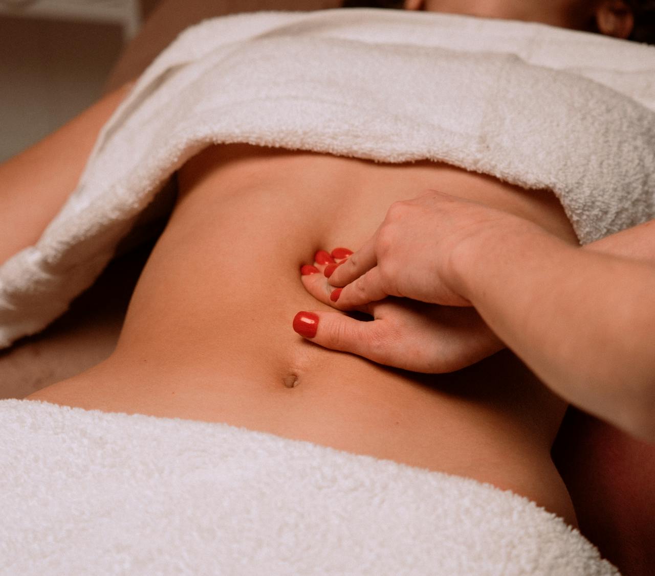 Mastering the First Impression: Your intriguing post title goes here A soothing massage on a woman's abdomen with painted nails, creating a serene spa atmosphere.